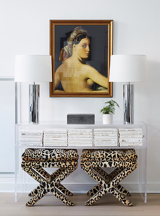 The artwork is definitely New Traditionalist, and the leopard-print ottomans would fit right in as well. The sleek chrome cylinder table lamps and the minimalist (and nearly invisible) acrylic console, however, bring Curator chic to the vignette. Room by One Kings Lane Interior Design. Photo by Manuel Rodriguez. 
